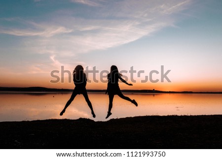 Girls are jumping into the skies. Dream moment on the sunset. Friendship and happines