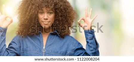 African american woman wearing blue jumpsuit doing ok sign gesture with both hands expressing meditation and relaxation