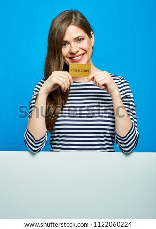 Smiling woman wearing striped shirt holding gold credit card with white banner below. Blue background.