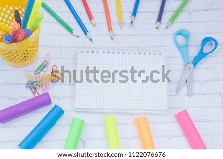 School supplies. Color markers, pencils, pens, blue scissors, yellow rubber, two blue ballpoint pens, color clips, notebook and tassels