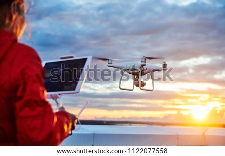 drone quadcopter with digital camera operated by woman at sunset