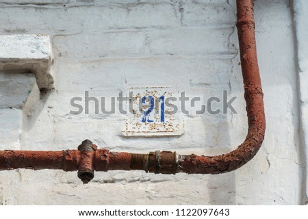 House № 21 old rusty sign on a white brick wall, twenty-one
