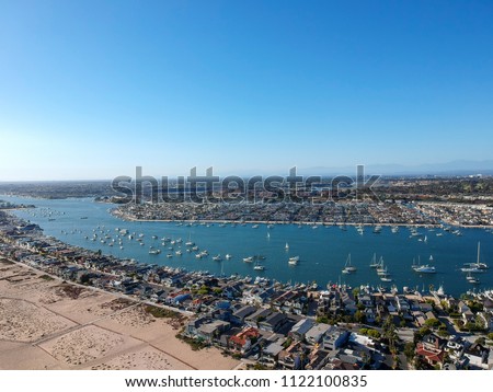 An aerial shot at 330 feet/100 meters looking out over the Newport skyline, the Balboa Peninsula and the Newport Bay full of boats. Captured in Southern California from an aeiral drone.
