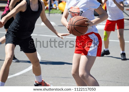 Girls teenagers basketball player play and train on the basketball court in the city on the street.