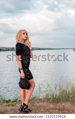 girl in black dress and hat in front of river 