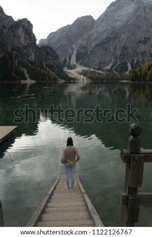 
The tourist woman standing at the pier and contemplating beautiful lake Braies, Italy. Lifestyle concept
