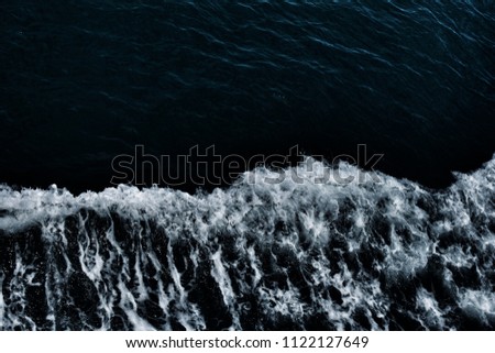 Half of blue sea and half of white waves from bird's eyes view. This is texture background and free space for designers. Image has grain or blurry or noise and soft focus when view at full resolution.
