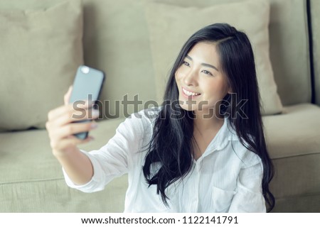 Selfie mania! Excited,Young attractive Asian woman making selfie on a smartphone camera or recording video vlog on a mobile phone. popular vlogger smiling to followers communicating by webcam online 