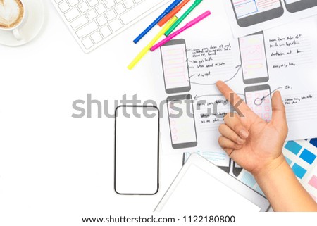 Working desk with hand pointing to sketch layout design mockup on smartphone screen,Mobile responsive website development with UI/UX