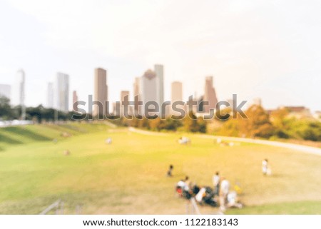 Vintage blurred people having picnic on green lawn urban park with downtown skyline in background. Friends Outdoor Nature Picnic Chilling Out Unity Concept, healthy lifestyle at Houston, Texas, USA
