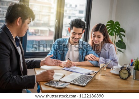 Asian young couple sign contact of home purchase or rental whihc have Sale representative offer the condition in document on the working space table in new place,Moving and House Hunting concept,