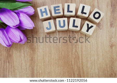 hello july with artificial flower on wooden background