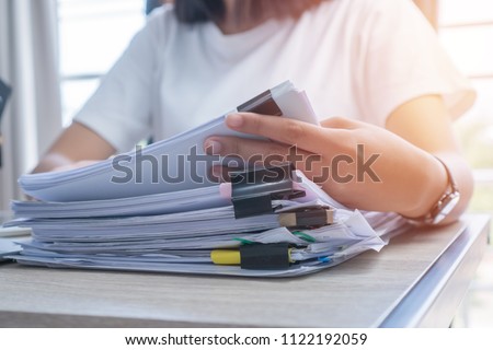 Business Documents concept : Employee woman hands working in Stacks paper files for searching and checking unfinished document achieves on folders papers at busy work desk office. Soft focus Royalty-Free Stock Photo #1122192059