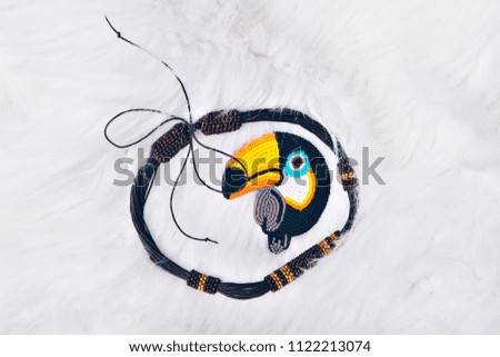 fabric texture as background. Blue and grey flax. Item of clothing close-up. bird Toucan made of beads and a lightning strike.. Symbol on blue background