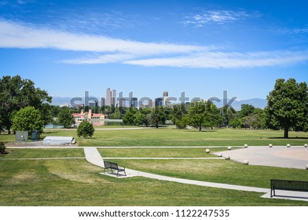 Denver Colorado cityscape skyline from east side with mountains in the summer with blue sky and green grass from a park