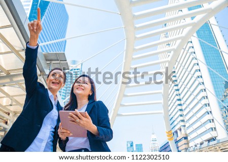 Businesswoman in town.They are standing on walkway.She  standing with partner.She is point the finger in to sky. Photo concept team work and Business.