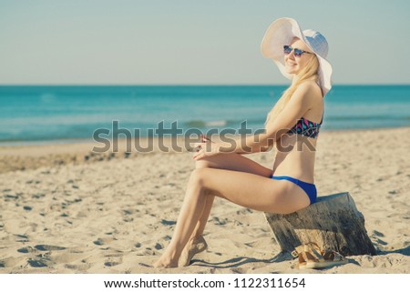 Portrait of young attractive woman relaxing and sunbathing on the beach. Toned in vanilla colors