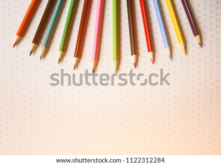 Color pencils lying on cute spotted background with dots. Back to school concept. Colorful art studying and painting process. Copy space place for postcard wish. Horizontal photo.