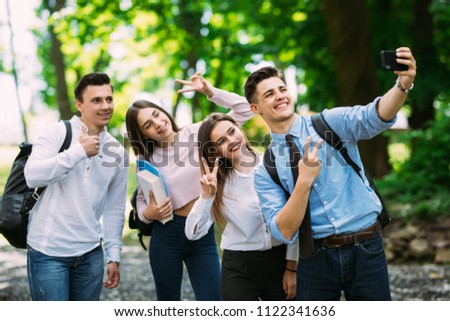 Cheerful young friends photographing themselves near university