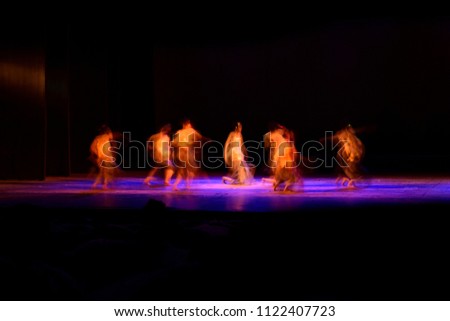 Dancers are dancing against black background. Photograph is taken with long expose, motion blur. 