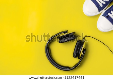 A pair of new stylish sneakers and headphones on a yellow bright background. Top view. Concept walks to music. Copy space Royalty-Free Stock Photo #1122417461