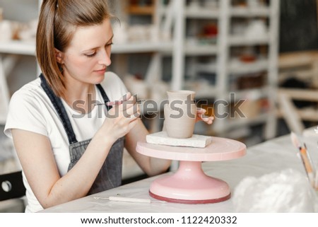 Workshop of clay pottery ceramic, woman decorating dishware pot