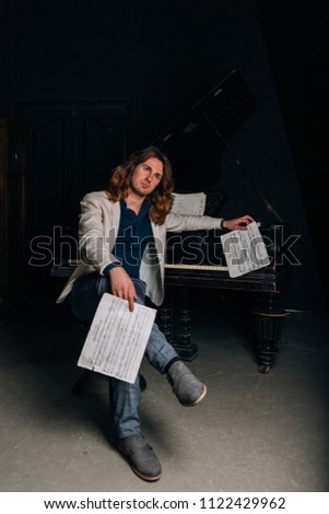 man near a black piano looks notes