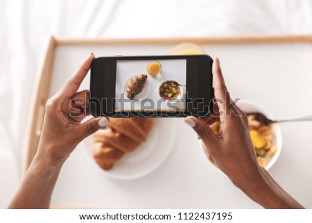 Close up of an african woman taking a picture of her breakfast in bed