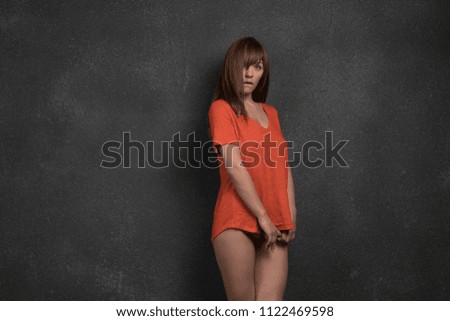 young beautiful girl posing in studio, standing in orange t-shirt