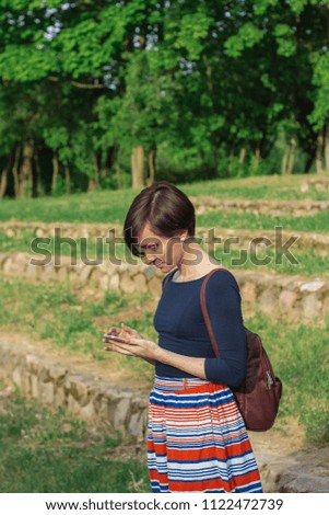 Woman holding smartphone cellular close up outdoors park green background. Female hands typing mobile phone touch screen device gadget. Technology communication concept copy space