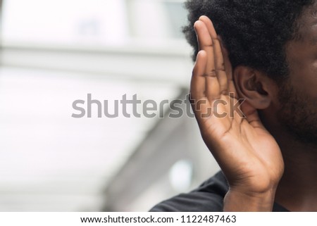 african man hearing or listening; portrait man listening to hearsay, rumor, gossip, good or bad news; communication, information, rumor concept; african man or black man young adult model