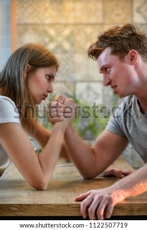 Arm wrestling challenge between young man and woman, couple household conflict and fight
