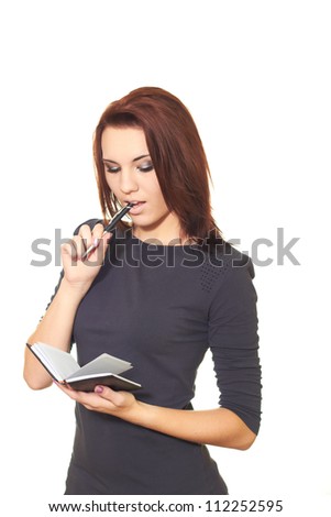 Attractive girl in a gray dress holding a pen and notebook and something in it reads. Isolated on white background