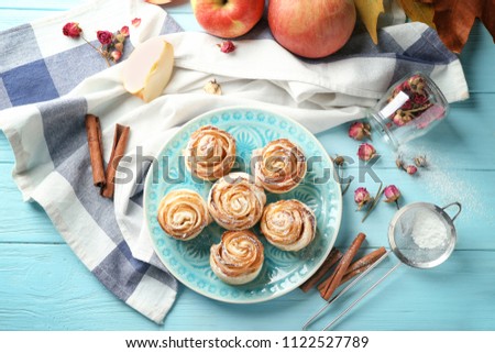 Plate with apple roses from puff pastry on color wooden table