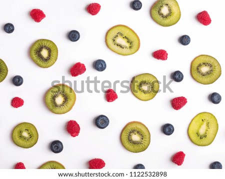 Creative fruit pattern with berries and sliced kiwis