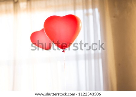 Heart Shaped Red balloons flying on blurred window background