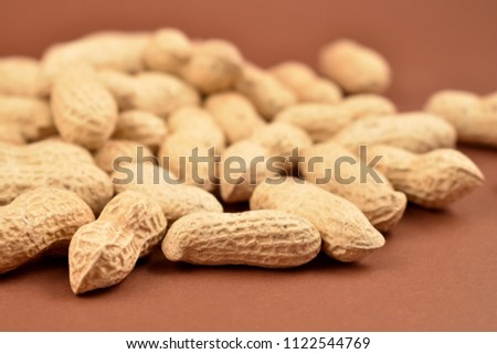 Peanuts on a brown background stock images. Pile of peanuts with nutshell. Roasted Peanuts close up on brown background