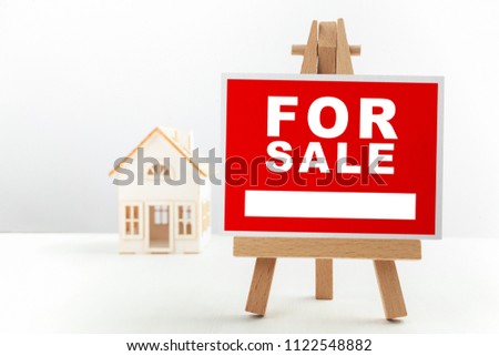 Red For Sale Real Estate Sign in Front of Small House Model.