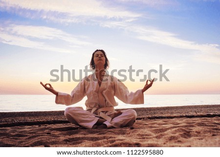 silhouette of a Girl dressed in a kimono in a Lotus position on the sandy shore of the ocean. The concept of a healthy lifestyle, unity with nature, meditation.