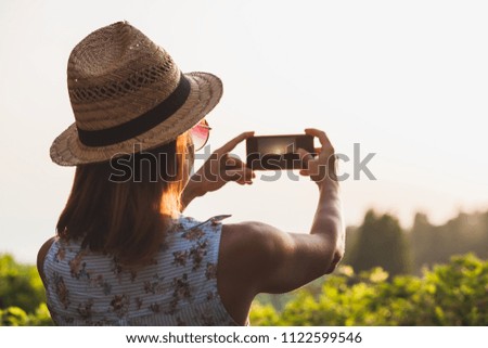 Young female tourist taking a photo of a beautiful sunset