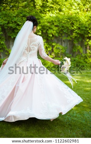 Beautiful bride with wedding bouquet in the green garden
