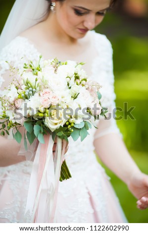 Beautiful bride with wedding bouquet in the green garden