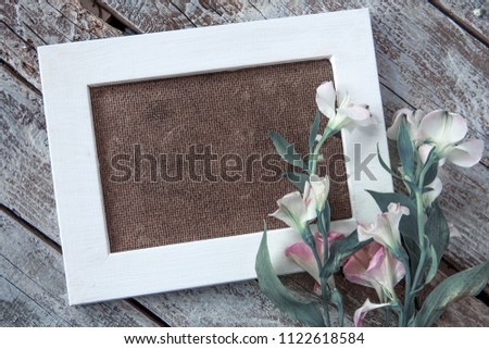 Blank photo frame and white flowers over wooden table background