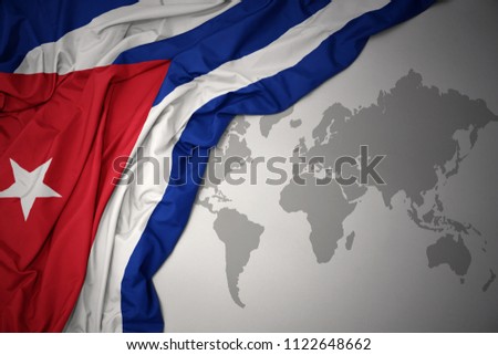 waving colorful national flag of cuba on a gray world map background.