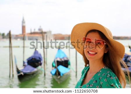 Smiling woman with sunglasses and hat looking at camera with Venice Lagoon on the background