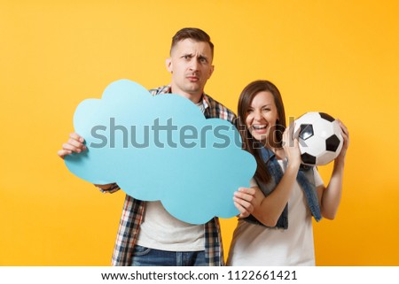 Young cheerful couple, woman man, football fans holding empty blank Say cloud, speech bubble, cheer up support team, soccer ball isolated on yellow background. Sport family leisure lifestyle concept