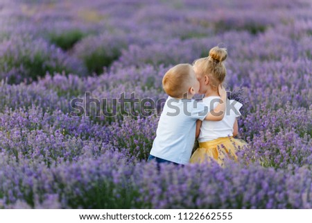 Playful little cute couple boy girl walk on purple lavender flower meadow field background, have fun, play, enjoy good sunny day. Excited small kids. Family day, children, childhood lifestyle concept