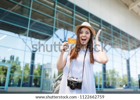Young shocked traveler tourist woman with retro vintage photo camera, spreading hands, holding credit card at international airport. Passenger traveling abroad on weekends getaway. Air flight concept
