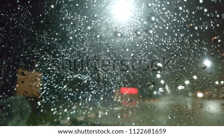 Blurred light with rain drops on the car window in the night of rainy weather. 