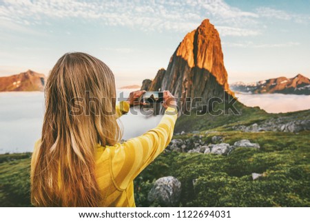 Woman blogger taking photo by smartphone exploring sunset mountains in Norway adventure trip summer vacations traveling lifestyle modern technology 